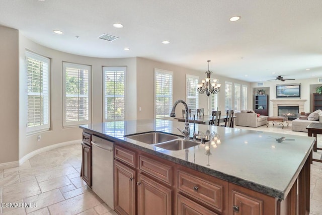 kitchen with pendant lighting, a kitchen island with sink, ceiling fan with notable chandelier, sink, and stainless steel dishwasher