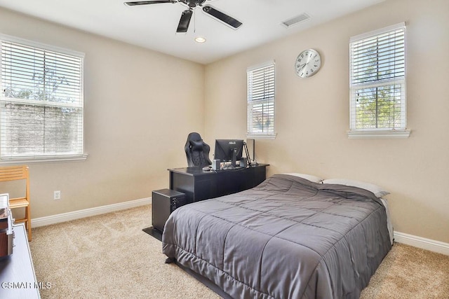 carpeted bedroom featuring multiple windows and ceiling fan