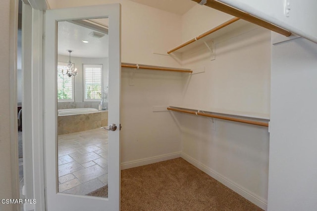 walk in closet featuring carpet flooring and an inviting chandelier