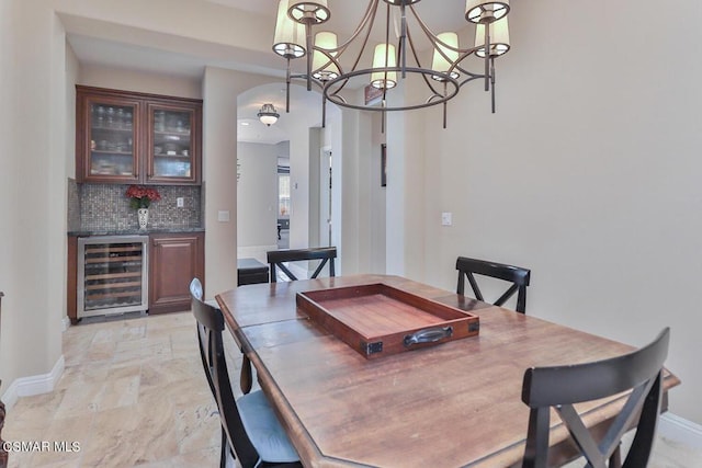 dining area featuring bar, wine cooler, and an inviting chandelier