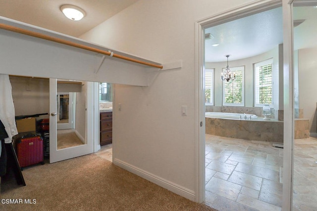 hallway featuring a notable chandelier and light colored carpet