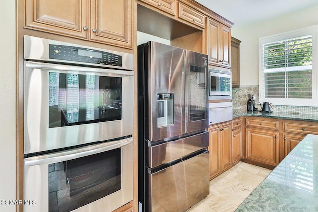 kitchen featuring decorative backsplash, dark stone counters, and appliances with stainless steel finishes