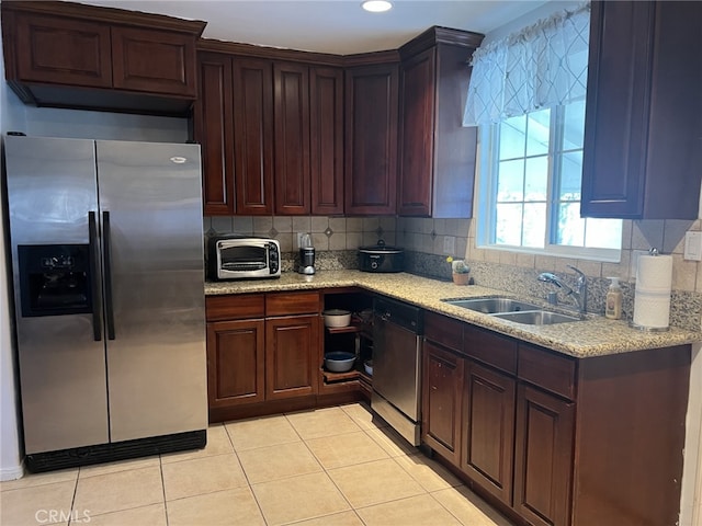 kitchen featuring light stone counters, light tile patterned floors, sink, backsplash, and stainless steel appliances