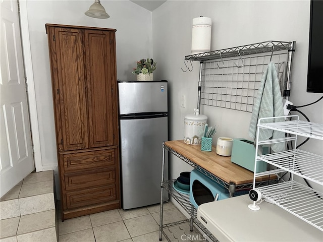 kitchen featuring light tile patterned flooring, stainless steel fridge, and wood counters