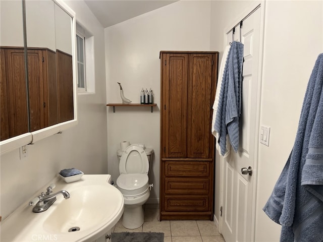 bathroom featuring toilet, tile patterned flooring, vaulted ceiling, and sink