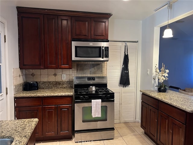 kitchen with appliances with stainless steel finishes, light tile patterned flooring, light stone countertops, and tasteful backsplash