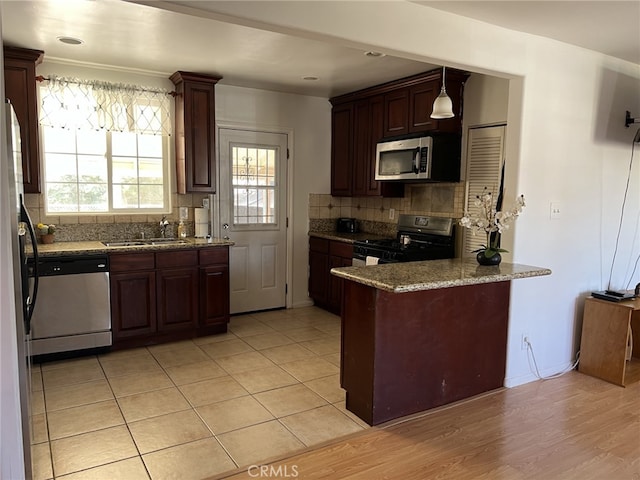 kitchen featuring decorative backsplash, pendant lighting, stainless steel appliances, light hardwood / wood-style flooring, and sink