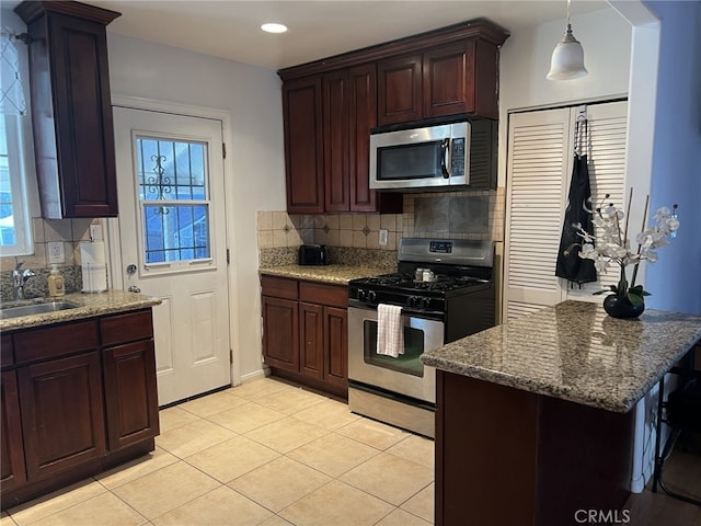 kitchen featuring pendant lighting, sink, stone countertops, backsplash, and stainless steel appliances