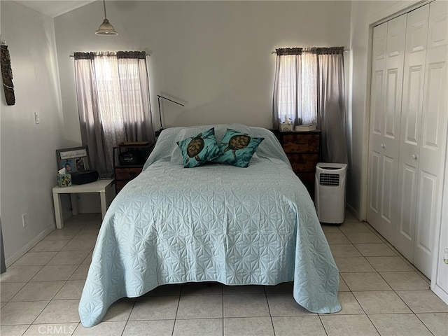 tiled bedroom featuring multiple windows, vaulted ceiling, and a closet