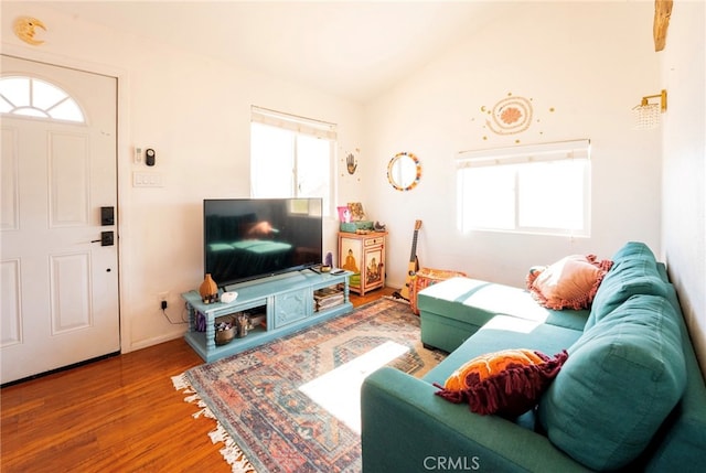 living room with a healthy amount of sunlight, wood-type flooring, and vaulted ceiling