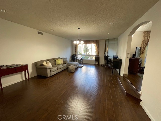 living room with a notable chandelier, a textured ceiling, and dark hardwood / wood-style flooring