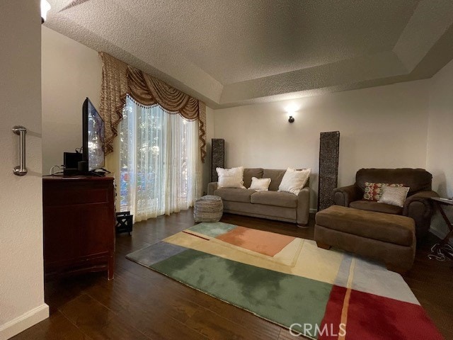 living room featuring a tray ceiling, dark hardwood / wood-style flooring, and a textured ceiling