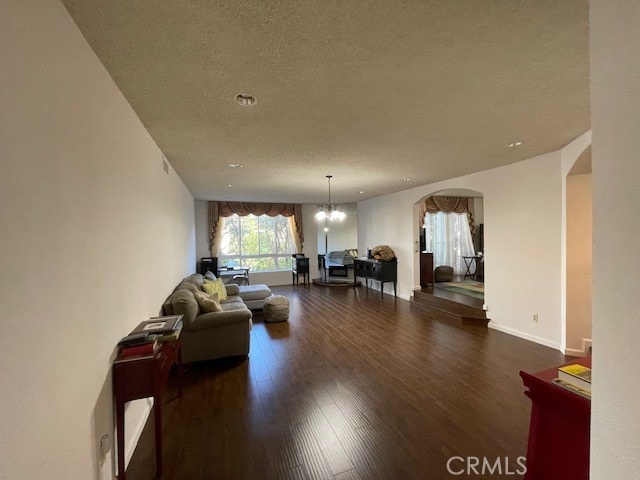 living room with a notable chandelier, dark hardwood / wood-style flooring, and a textured ceiling