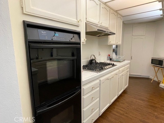 kitchen with dark wood-type flooring, white cabinets, appliances with stainless steel finishes, and tile counters