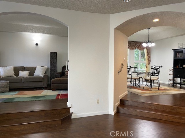 living room featuring hardwood / wood-style floors, an inviting chandelier, and a textured ceiling