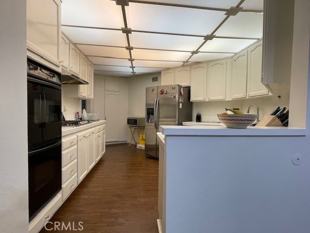 kitchen featuring white cabinets, appliances with stainless steel finishes, dark hardwood / wood-style flooring, and kitchen peninsula