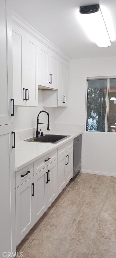 kitchen with white cabinetry, sink, and stainless steel dishwasher