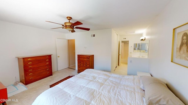 bedroom with light carpet, ensuite bath, and ceiling fan