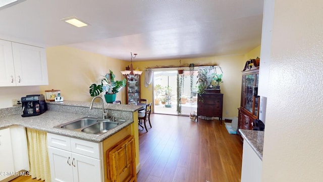 kitchen with sink, an inviting chandelier, light hardwood / wood-style flooring, white cabinetry, and hanging light fixtures