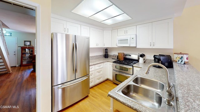 kitchen featuring sink, white cabinets, stainless steel appliances, and light hardwood / wood-style flooring