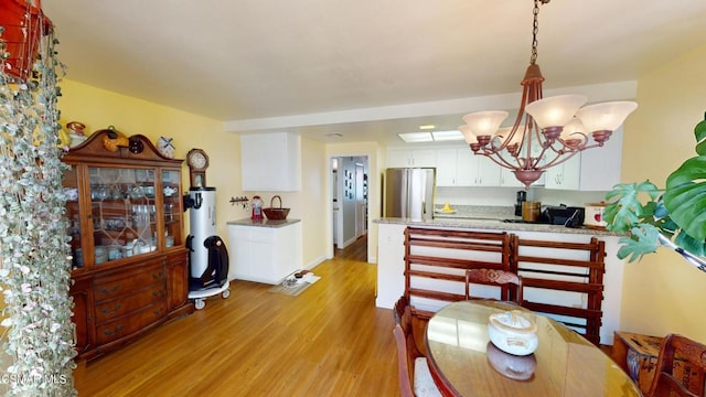 dining area with light hardwood / wood-style floors, gas water heater, and a chandelier