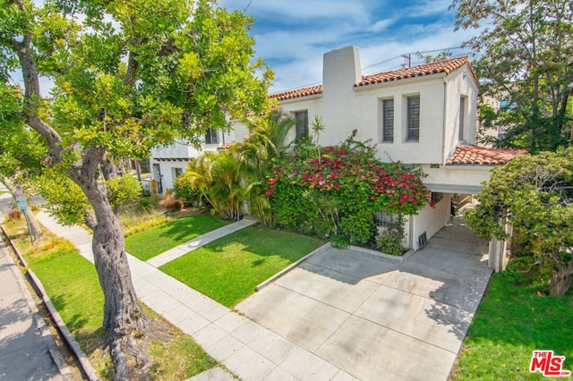 mediterranean / spanish-style home with a front lawn and a carport