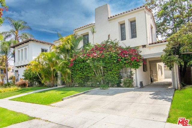 mediterranean / spanish-style house featuring a carport and a front yard