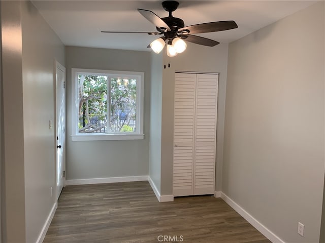 unfurnished bedroom with ceiling fan, a closet, and dark wood-type flooring