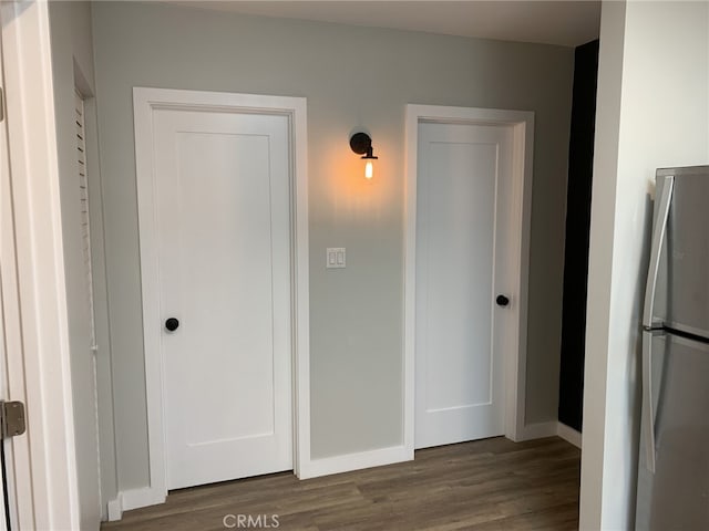 unfurnished bedroom with stainless steel fridge and dark hardwood / wood-style flooring