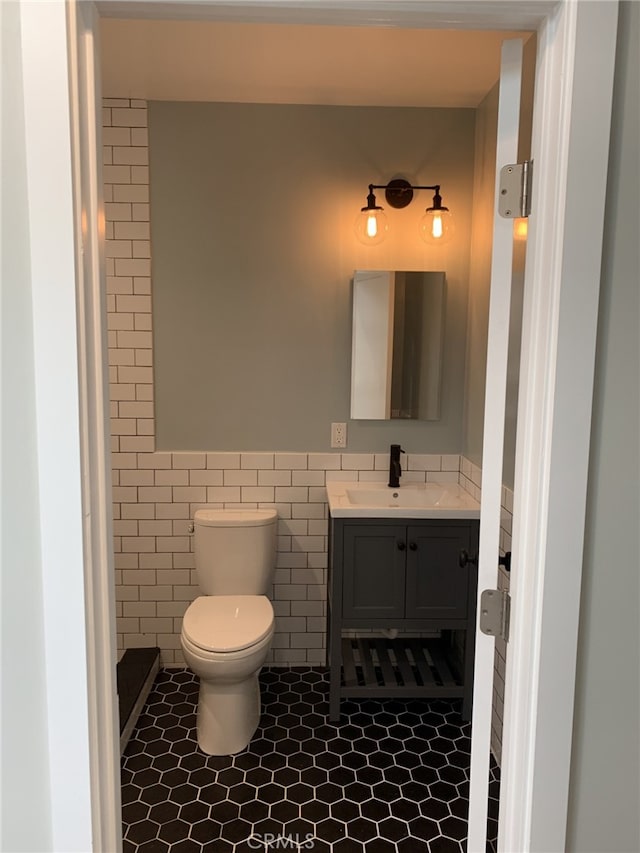 bathroom featuring tile patterned floors, vanity, toilet, and tile walls