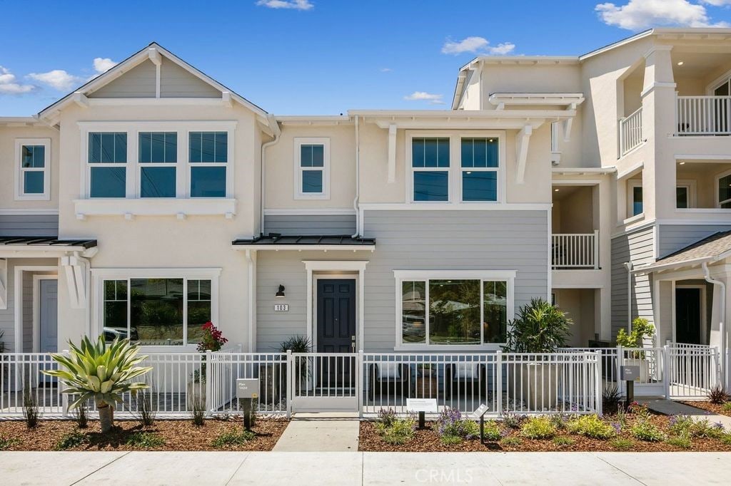 townhome / multi-family property with fence private yard, metal roof, stucco siding, and a standing seam roof