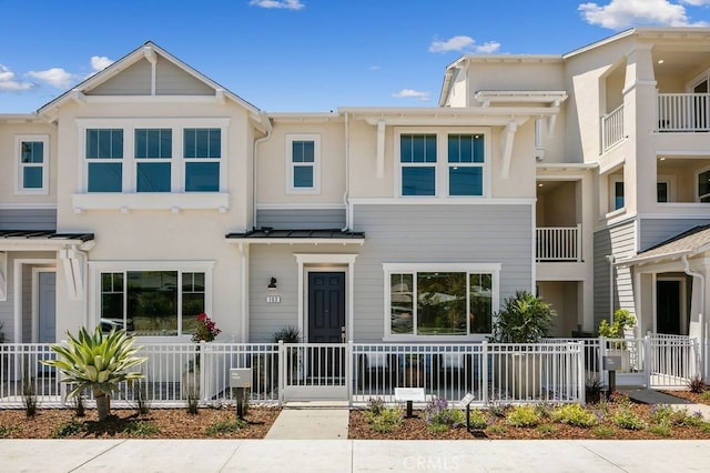 townhome / multi-family property with fence private yard, metal roof, stucco siding, and a standing seam roof