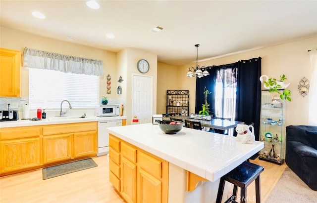 kitchen with a kitchen island, white appliances, decorative light fixtures, a chandelier, and light hardwood / wood-style floors