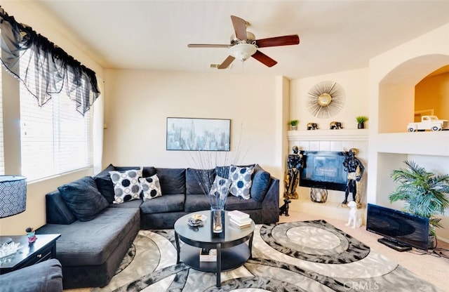 living room featuring a tile fireplace and ceiling fan