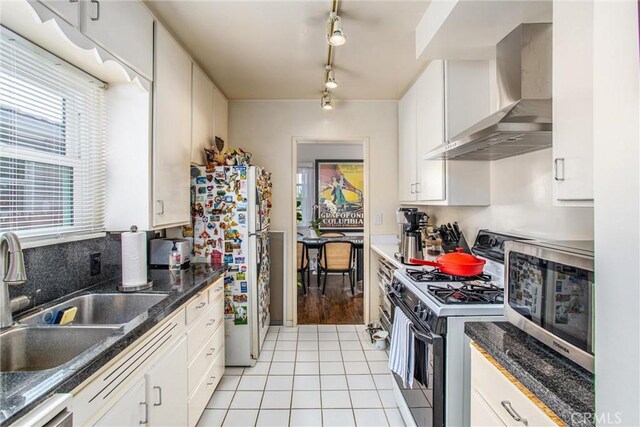 kitchen with sink, wall chimney range hood, white cabinets, and stainless steel appliances