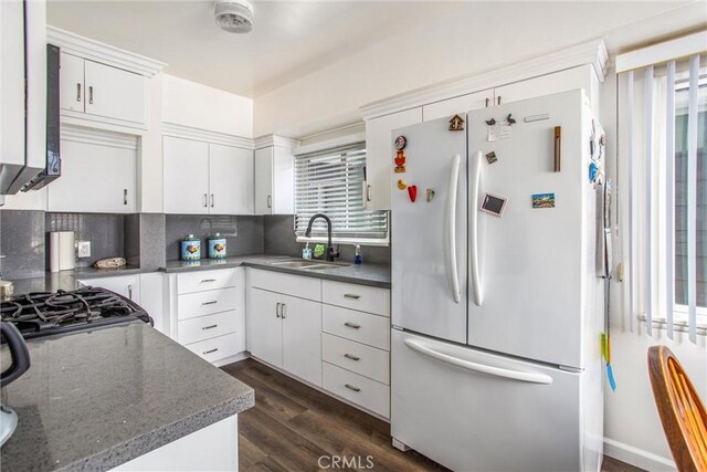 kitchen with white fridge, decorative backsplash, sink, white cabinetry, and dark wood-type flooring