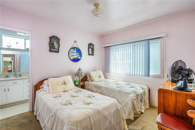 carpeted bedroom with ensuite bath, sink, and multiple windows