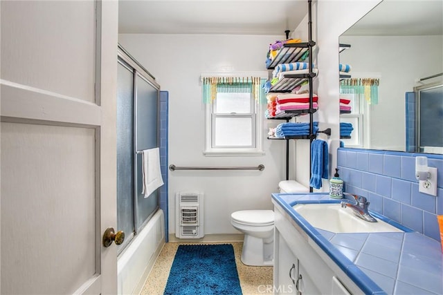 full bathroom with toilet, enclosed tub / shower combo, decorative backsplash, heating unit, and vanity