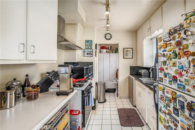 kitchen with wall chimney range hood, white cabinetry, appliances with stainless steel finishes, track lighting, and light tile patterned floors