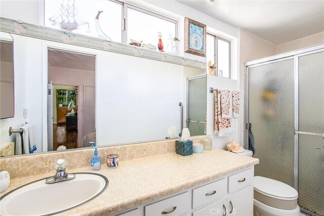 bathroom featuring toilet, walk in shower, and vanity