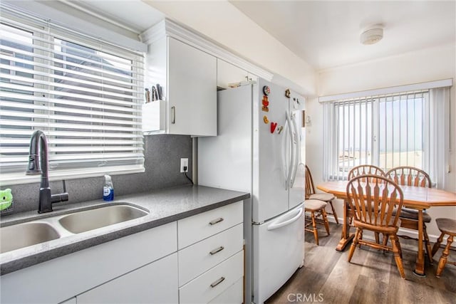 kitchen with dark wood-type flooring, white cabinetry, white fridge, a healthy amount of sunlight, and sink