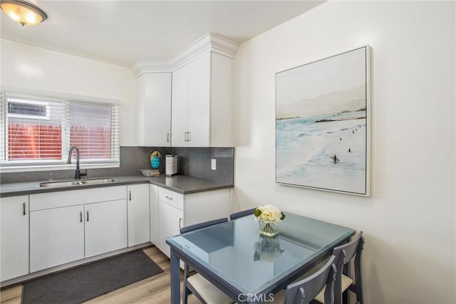 kitchen with sink, backsplash, white cabinets, and light wood-type flooring