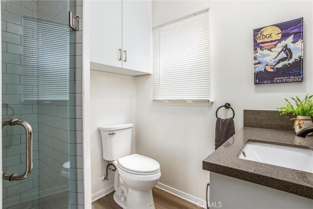 bathroom featuring a shower with door, hardwood / wood-style flooring, toilet, and vanity