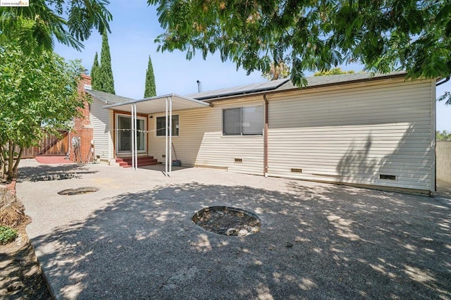 back of property with solar panels and a patio area