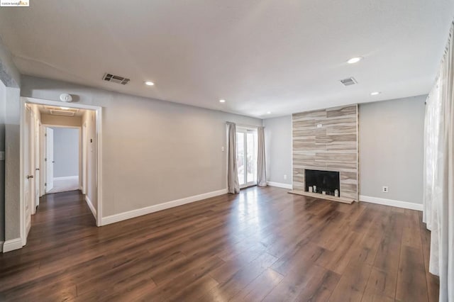 unfurnished living room featuring a tile fireplace and dark wood-type flooring