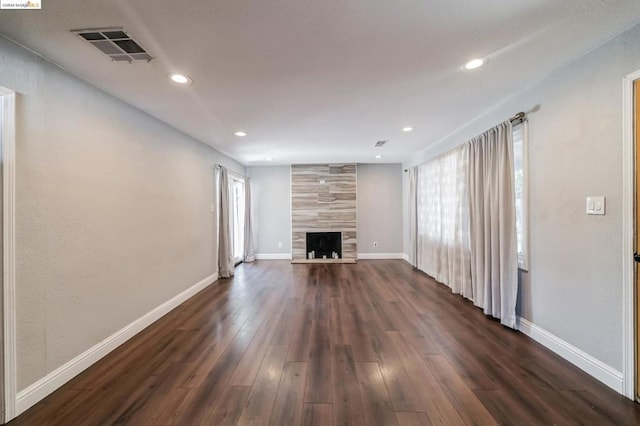 unfurnished living room with a tiled fireplace and dark wood-type flooring