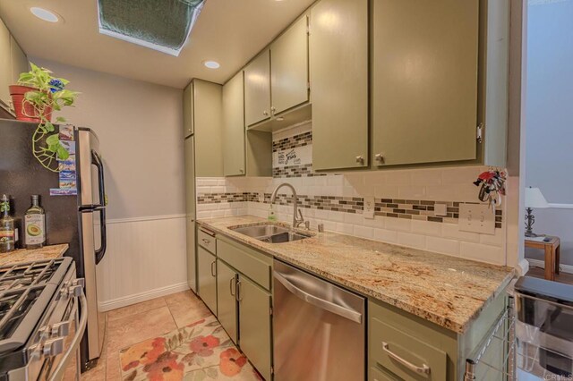 kitchen with light stone counters, decorative backsplash, sink, light tile patterned flooring, and appliances with stainless steel finishes