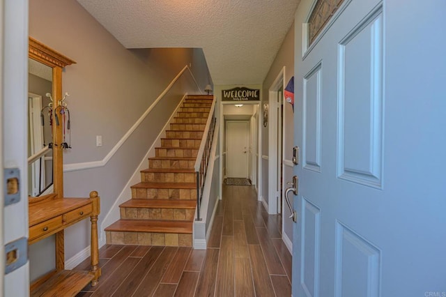 foyer entrance featuring a textured ceiling and dark hardwood / wood-style flooring