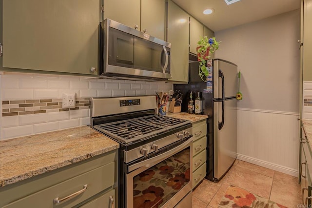 kitchen with light tile patterned flooring, light stone counters, decorative backsplash, and stainless steel appliances