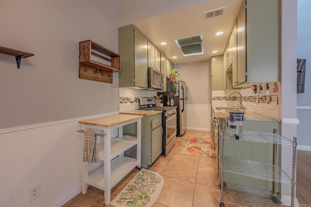 kitchen with butcher block counters, sink, light tile patterned flooring, appliances with stainless steel finishes, and backsplash